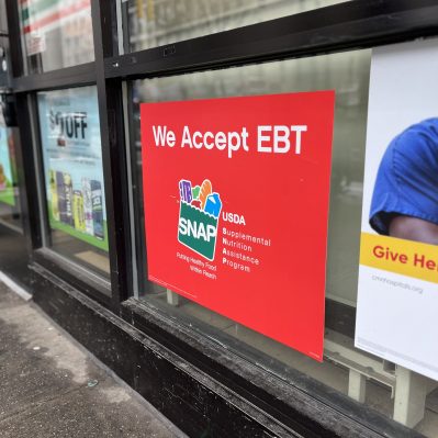 Sign in a storefront window that says "We Accept EBT" with the SNAP USDA logo.